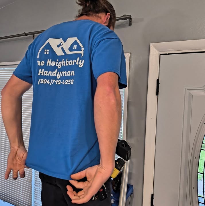 Business-published photo of a Neighborly Handyman team member at work indoors, wearing its blue branded shirt